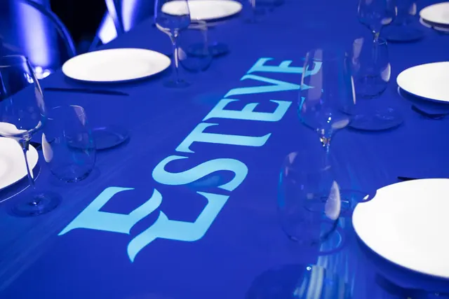 Dinner table with the Esteve logo projected in blue